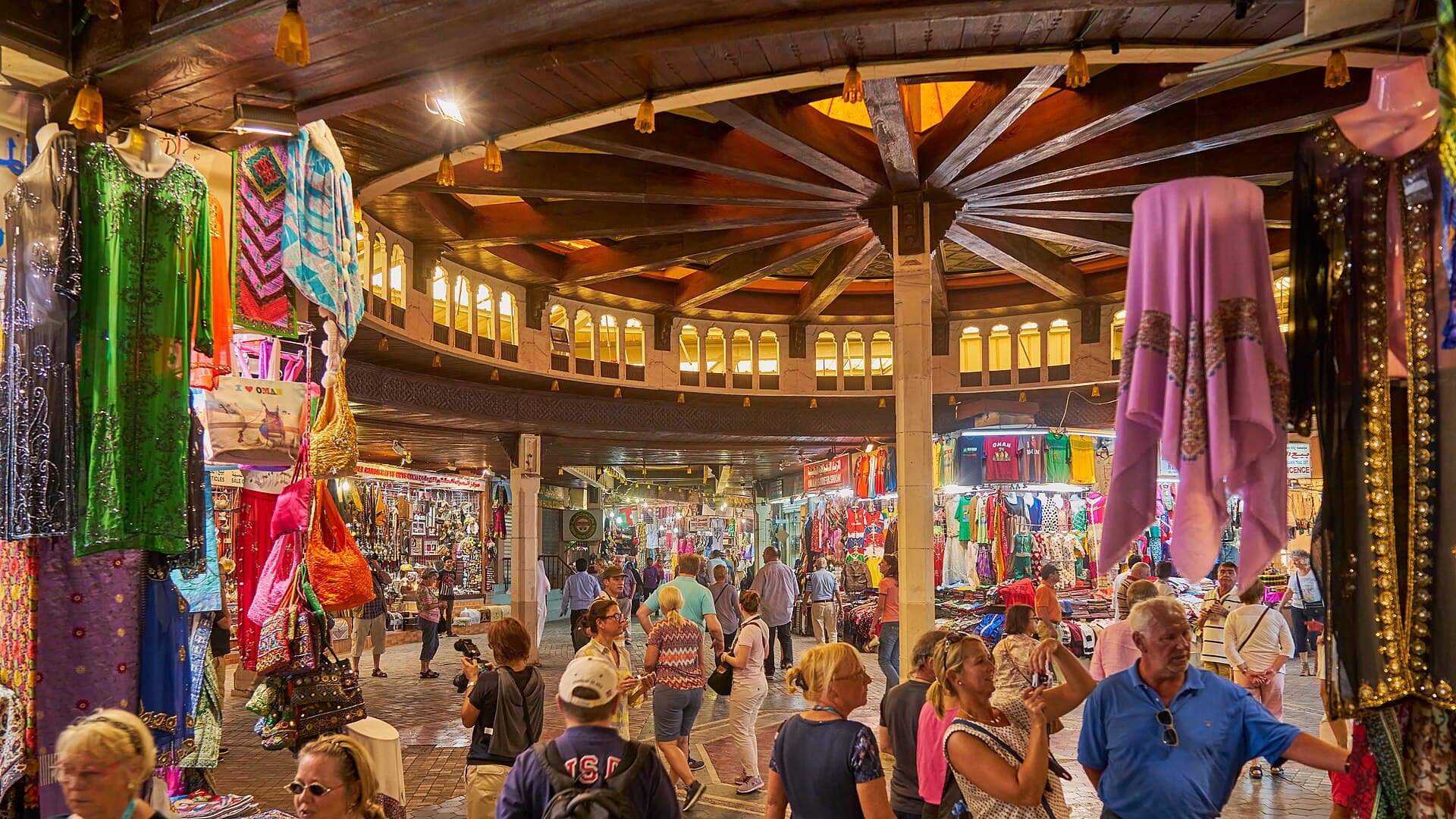 Inside Muttrah Souq with wooden ceiling, stalls, and shoppers